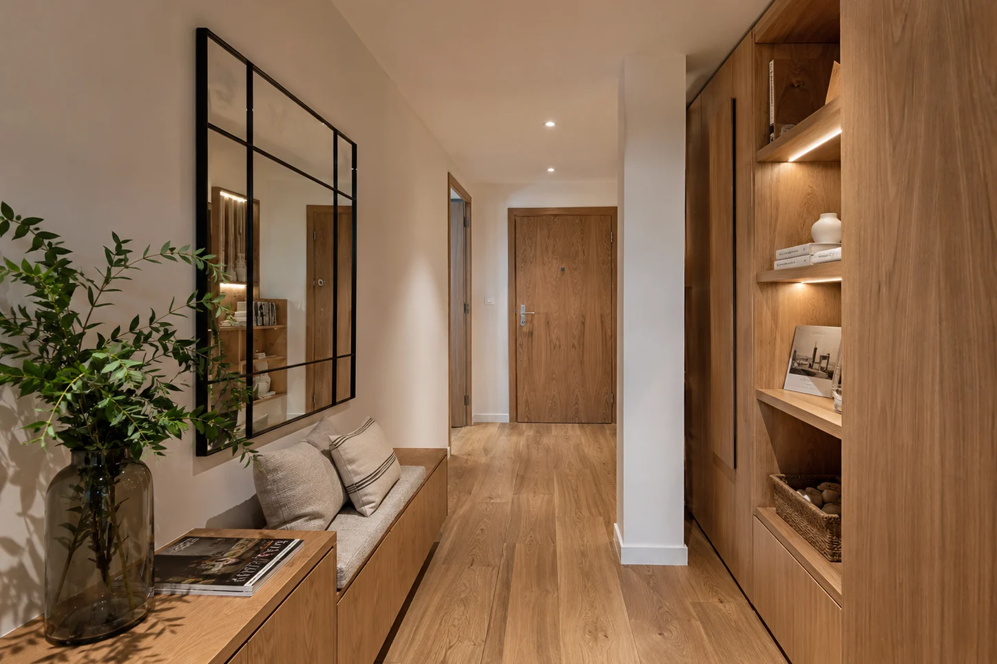 Pasillo con suelo de tarima de roble, banco bajo y estantería de madera